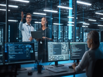 Female e-Business Entrepreneur and Male IT Specialist Discussing Something and Use Laptop in Big Data Center Server Room. Work on Web Services Cloud Computing SAAS Concept